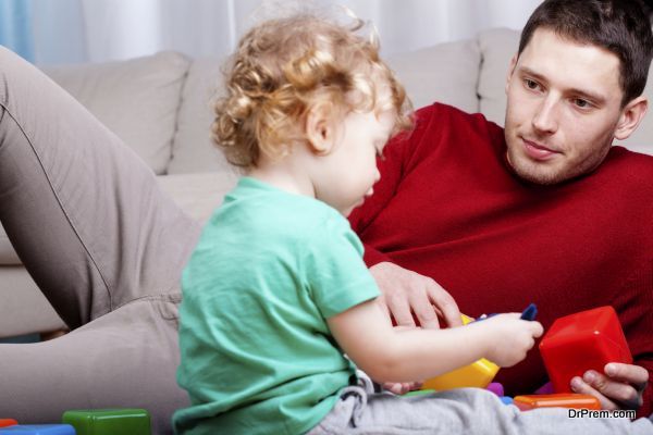 Dad looks at his son playing with blocks