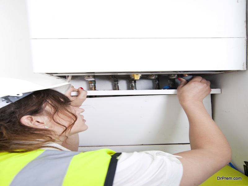 Female plumber servicing central heating boiler