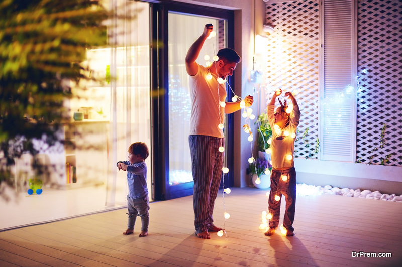 father and child hanging string lights