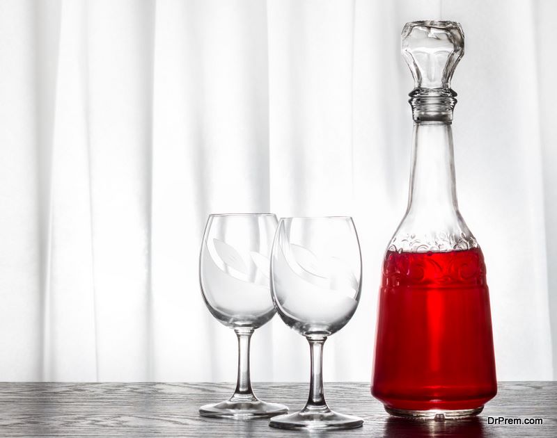 A carafe with wine and two glasses. Drawn curtains in the window. A romantic meeting by the wine.