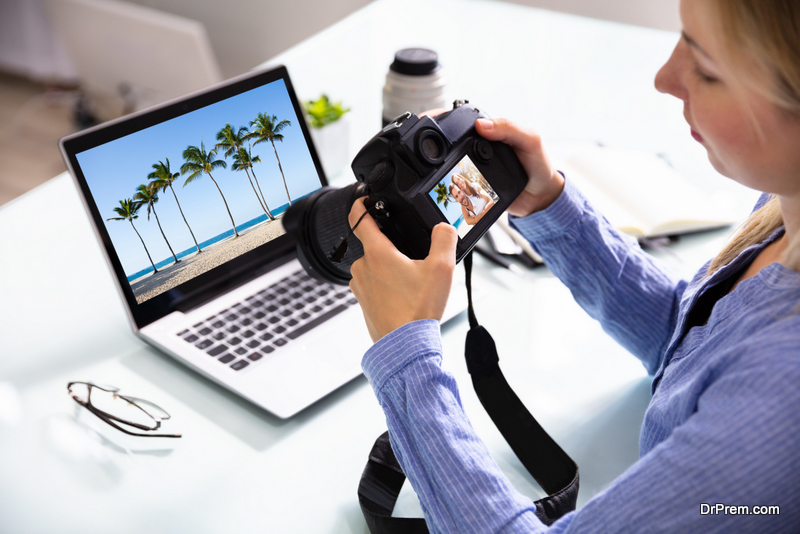 Female Editor Looking At Couple Photograph In DSLR Camera With Laptop On Desk
