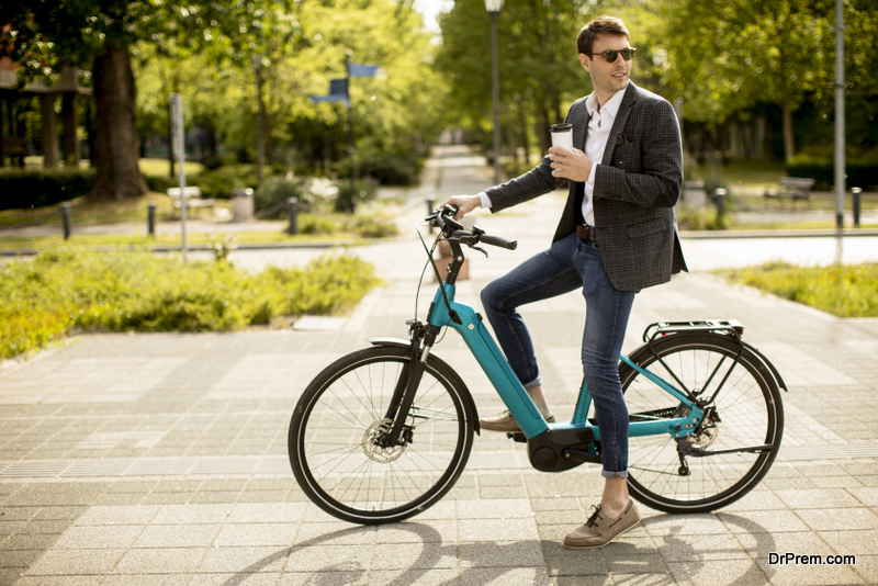 Handsome young businessman on the ebike with takeaway coffee cup