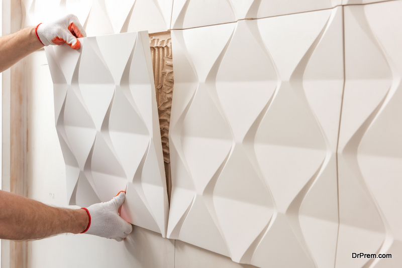 Installation of gypsum 3D panel. A worker is attaching the gypsum tile to the wall.