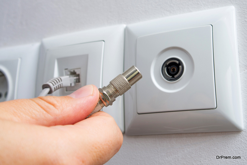 Man plugs television antenna cable or cable TV cord in the wall socket.